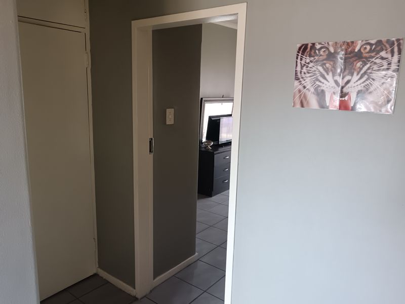 A functional hallway featuring tiled flooring and a built-in cupboard, providing access to adjacent living spaces.
