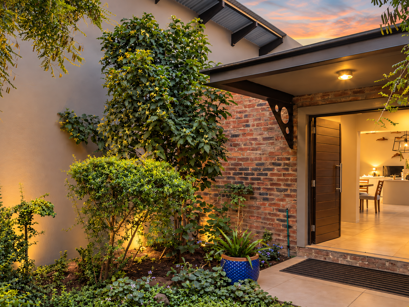 A beautifully landscaped rear patio area featuring exposed brickwork, modern lighting, and a seamless transition into the interior living space.