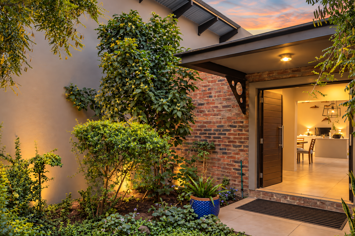 A beautifully landscaped rear patio area featuring exposed brickwork, modern lighting, and a seamless transition into the interior living space.