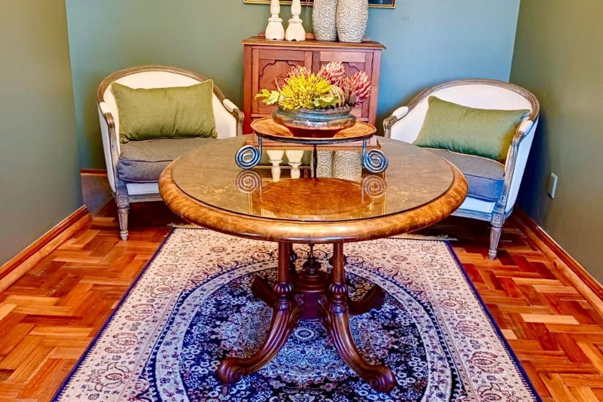 A cozy living area featuring warm-toned parquet flooring and classic green wall finishes, creating a traditional and inviting atmosphere.