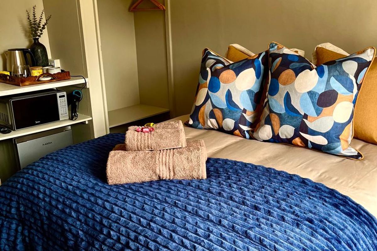 A cozy bedroom featuring a built-in wardrobe with overhead storage, providing functional space for guest accommodation.