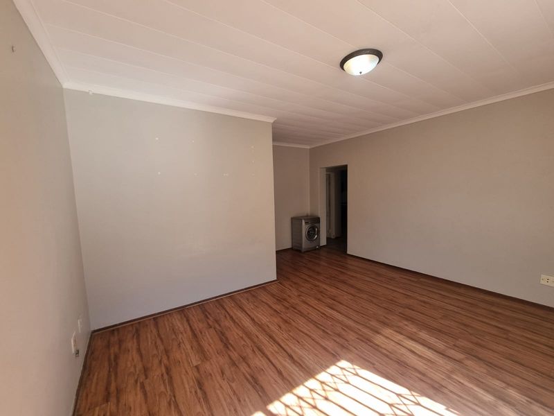 A spacious, empty living area featuring wood-look laminate flooring and a neutral color palette, ready for personalization.