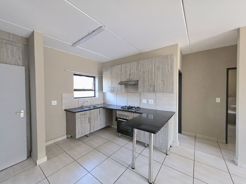 Modern kitchen featuring light wood-grain cabinetry, granite countertops, a gas hob, built-in oven, and a convenient breakfast nook with tiled flooring.