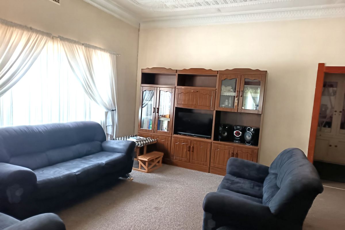 A spacious living room featuring high ceilings with decorative cornicing and a large window allowing for natural light.