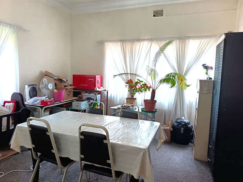 A functional dining room featuring large windows with natural light, neutral wall finishes, and carpeted flooring.