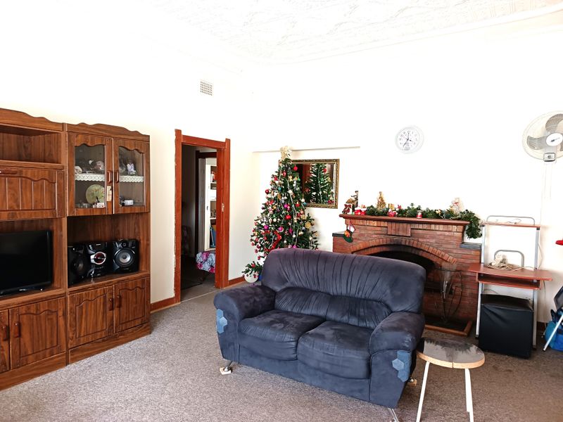 A living room featuring a traditional brick fireplace, carpeted flooring, and decorative ceiling detailing, providing a classic foundation for potential updates.