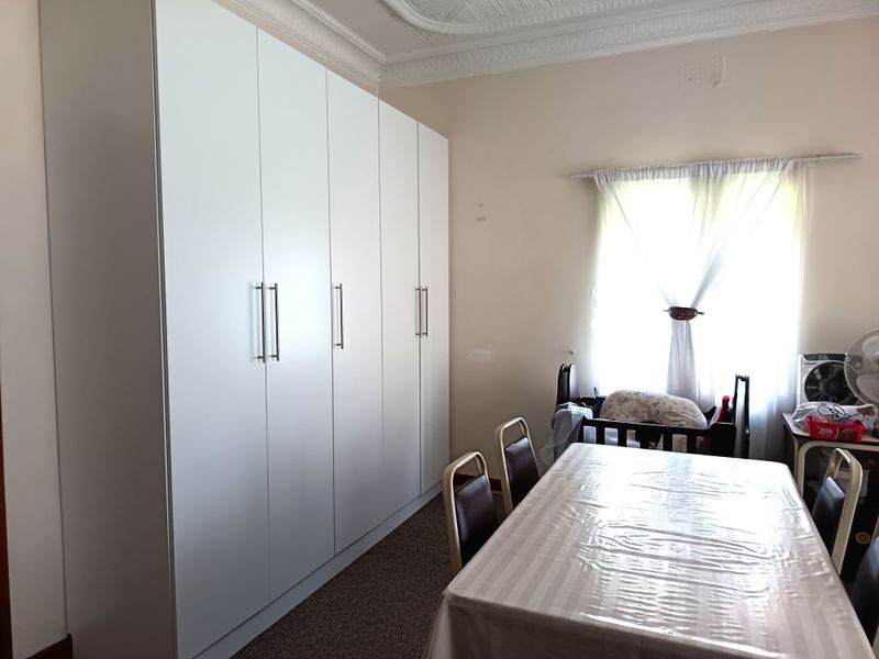 A bedroom featuring a large, modern floor-to-ceiling built-in wardrobe with white cabinetry and decorative ceiling cornicing.