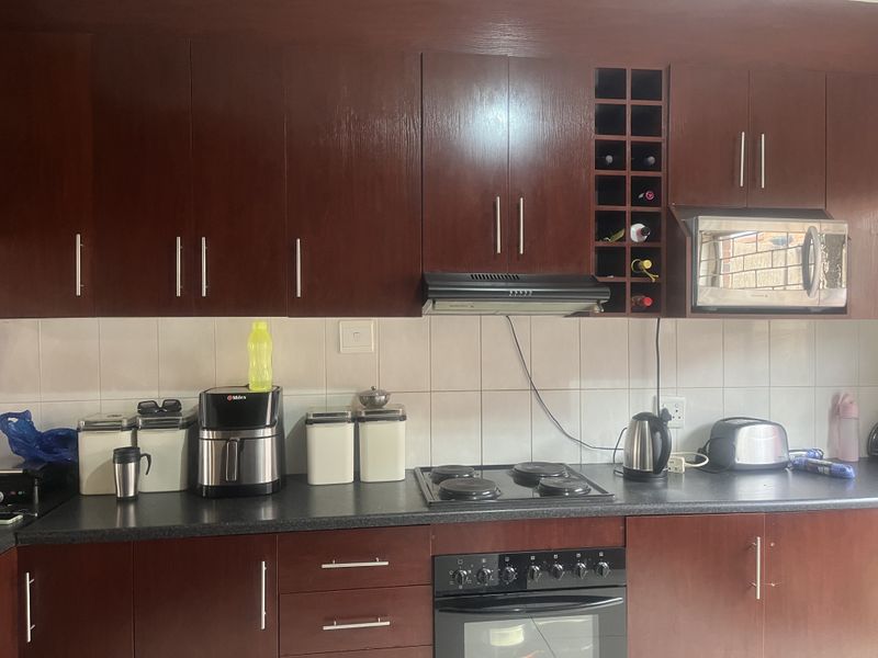 A functional kitchen featuring dark wood cabinetry, a tiled backsplash, built-in oven, electric hob, and integrated microwave with a dedicated wine rack.