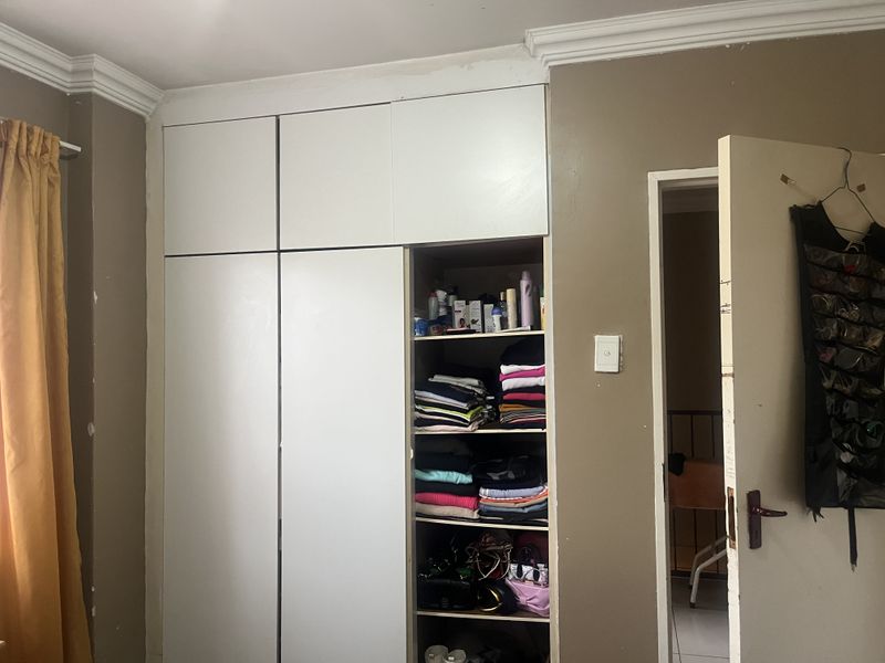 A bedroom featuring a built-in wardrobe with overhead storage and crown molding detail.