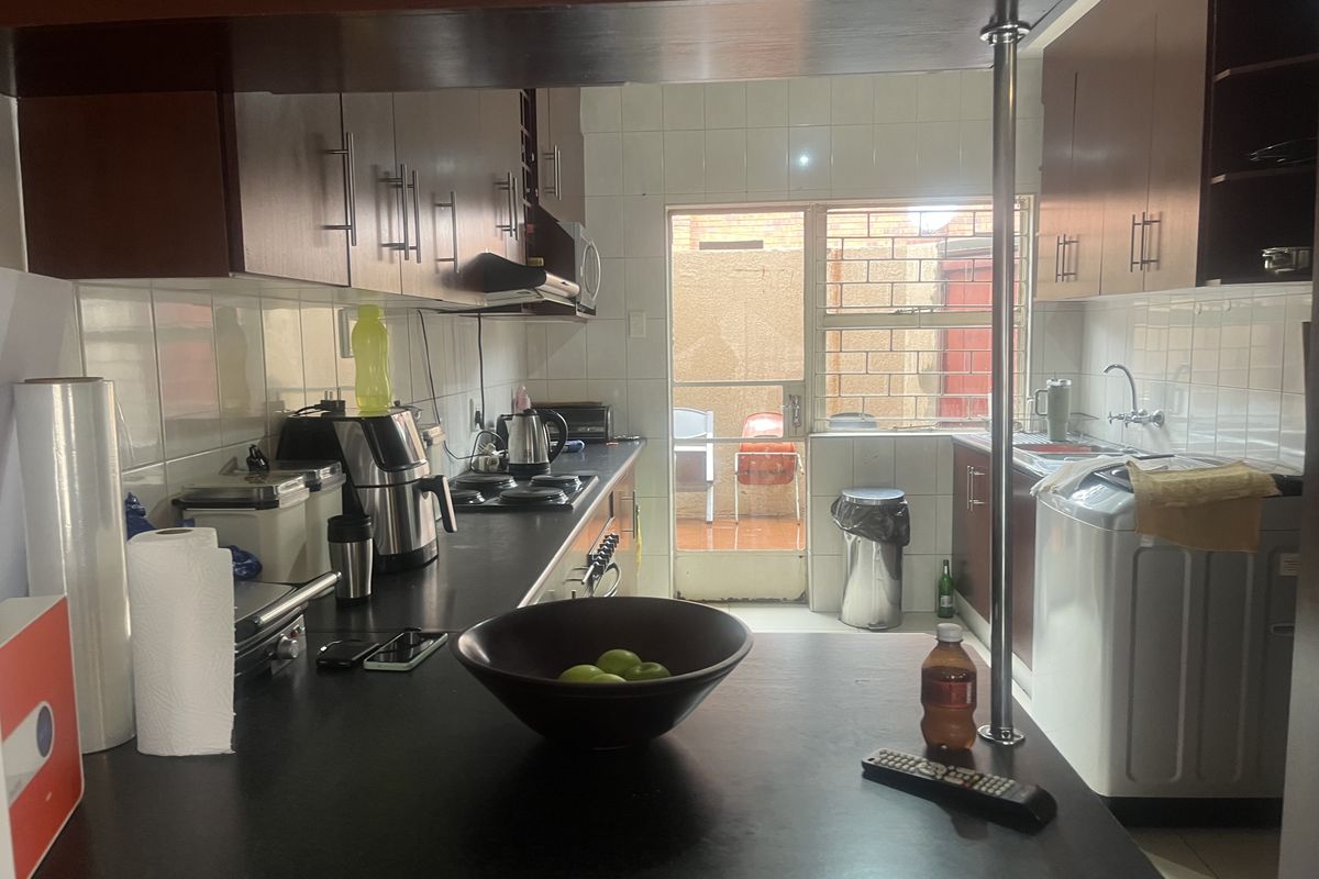 Functional kitchen featuring dark cabinetry, laminate countertops, a gas hob, and a breakfast bar, with direct access to an outdoor area.