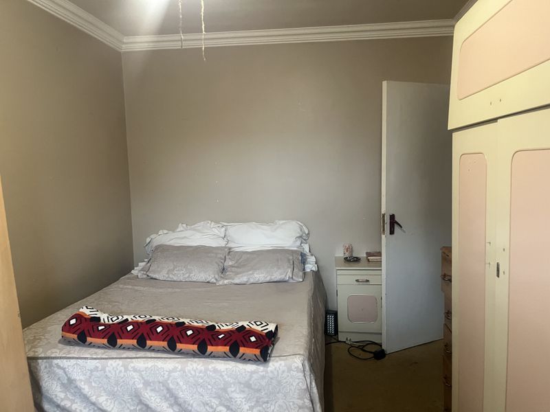 A bedroom featuring built-in wardrobe storage and crown molding, requiring cosmetic updates to the wall finishes and general maintenance.