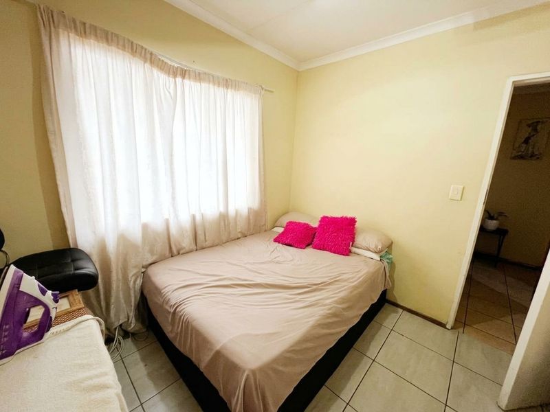 A compact bedroom featuring tiled flooring and neutral wall finishes, providing a functional space with natural light from the window.