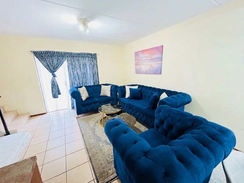 A living room featuring tiled flooring and a sliding glass door providing access to the exterior.