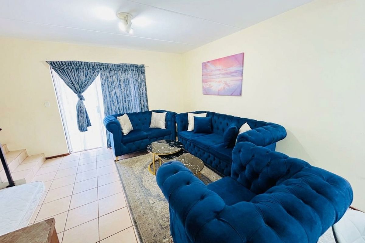 A living room featuring tiled flooring and a sliding glass door providing access to the exterior.