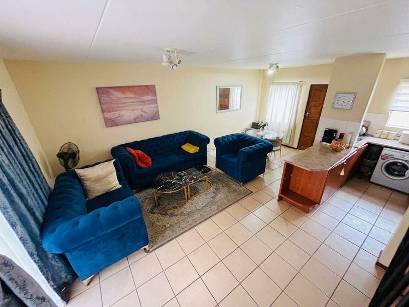 Open plan living area featuring tiled flooring and a functional kitchen with a breakfast island and integrated laundry connection.
