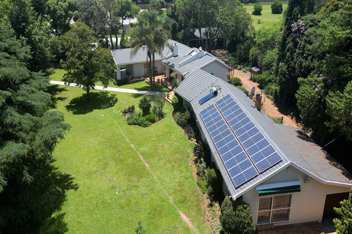 Aerial view of the property showcasing the expansive garden, tiled roof, and installed solar panel array.