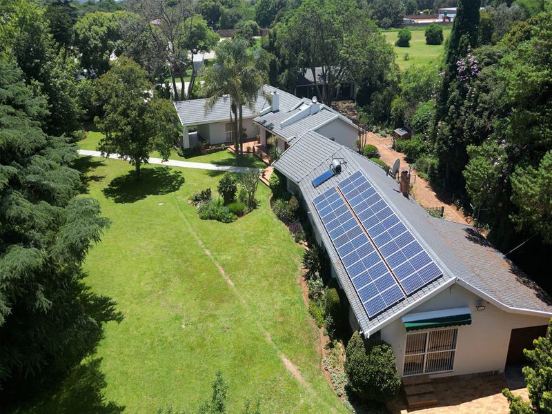 Aerial view of the property showcasing the expansive garden, tiled roof, and installed solar panel array.