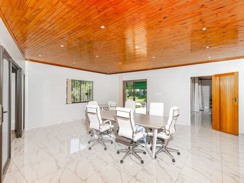 Spacious dining room featuring polished marble-look floor tiles, a warm timber-clad ceiling with recessed lighting, and direct access to the rear garden.