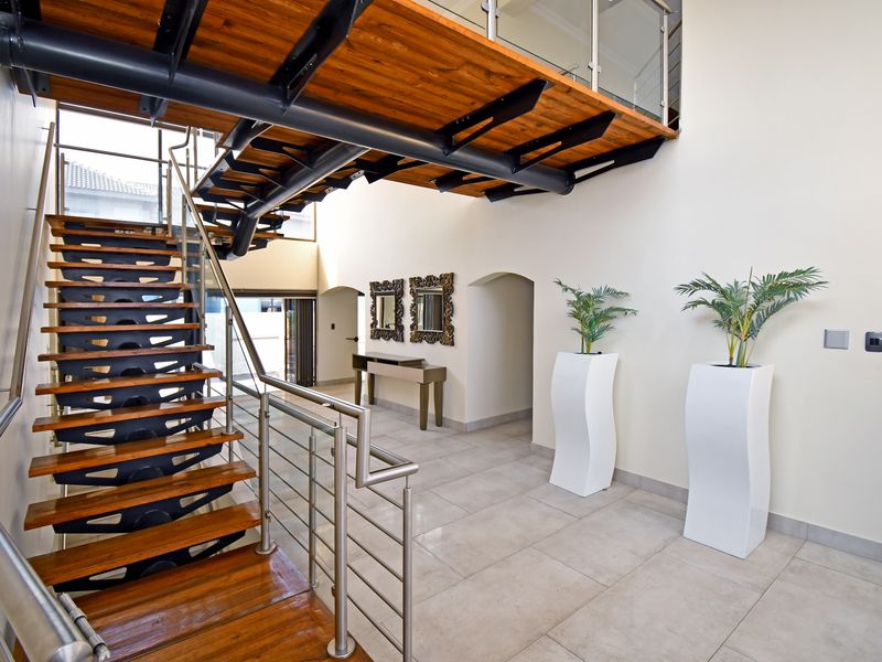 Spacious entrance hall featuring a striking floating timber staircase with steel framing and modern stainless steel and glass balustrades.