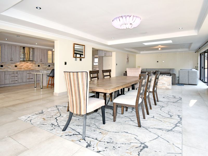 Spacious open-plan living and dining area featuring tiled floors, recessed lighting, and a modern kitchen with built-in cabinetry and stone backsplash.