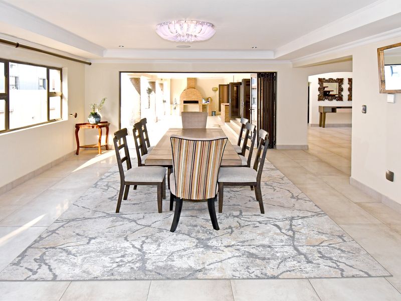 Spacious dining room featuring tiled flooring, a recessed ceiling, and large bi-fold doors that open to an outdoor entertainment area.