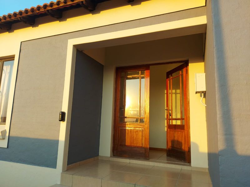 Front entrance featuring a tiled porch and a classic wooden framed glass door under a terracotta tiled roof overhang.