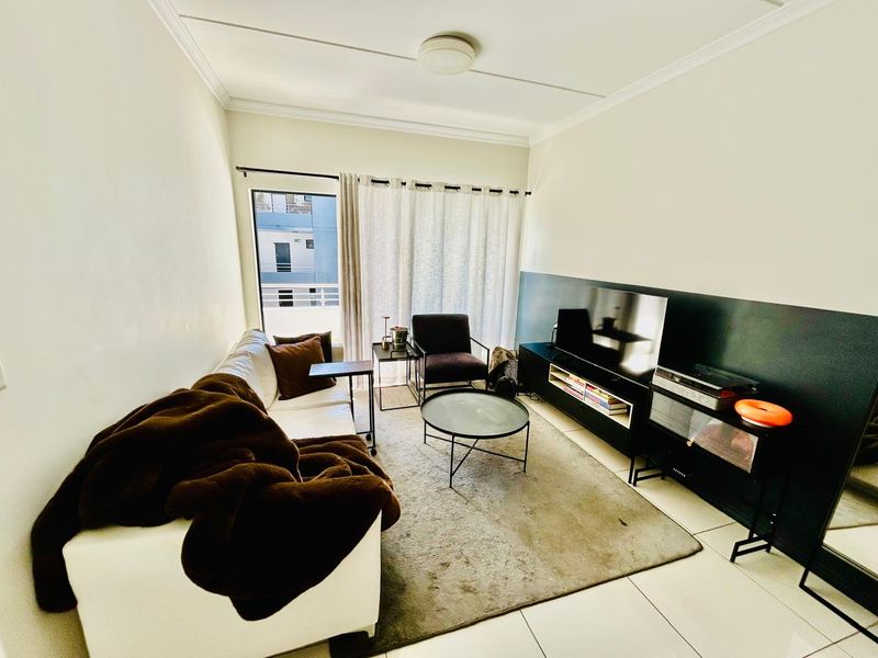 A well-lit living room featuring tiled flooring, a coved ceiling, and a sliding glass door providing access to an outdoor area.
