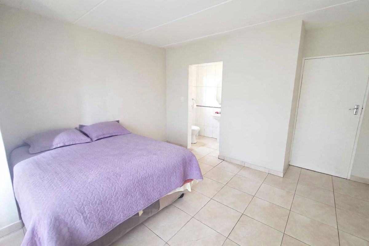 A bedroom featuring tiled flooring and direct access to an en-suite bathroom, offering a neutral and functional living space.