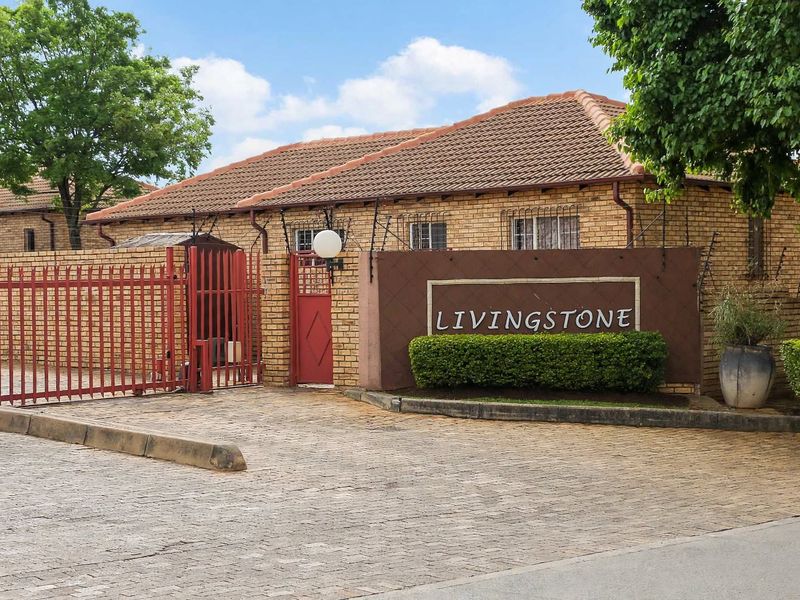 Front entrance view of the Livingstone apartment complex featuring a brick facade, tiled roof, and secure gated access.