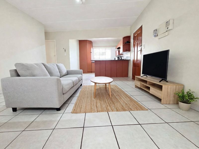 Open-plan living area featuring tiled flooring and a functional kitchen with built-in cabinetry and a breakfast counter.