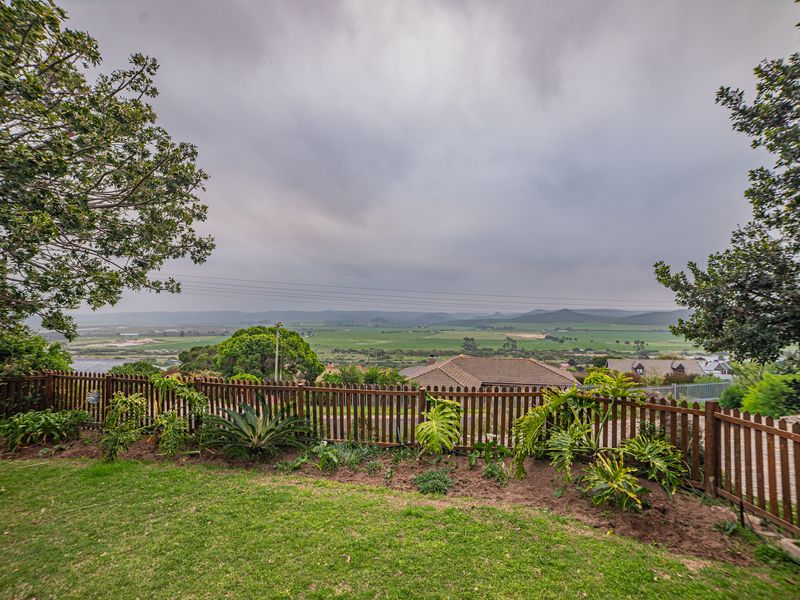 A scenic elevated view overlooking the surrounding valley and landscape, framed by a well-maintained garden and wooden picket fence.