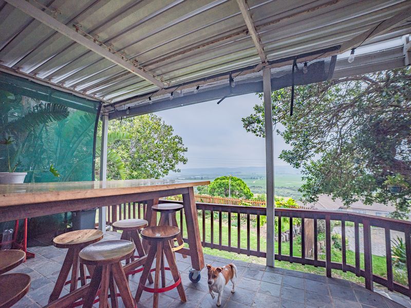 Covered outdoor patio featuring tiled flooring and a timber balustrade, offering elevated views of the surrounding landscape.