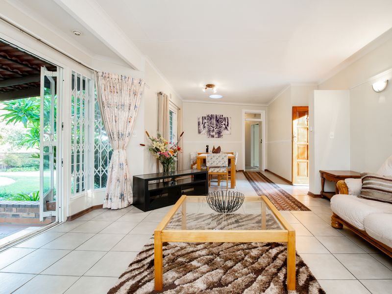 Spacious open-plan living and dining area featuring tiled floors, abundant natural light, and direct access to the outdoor patio through sliding glass doors.