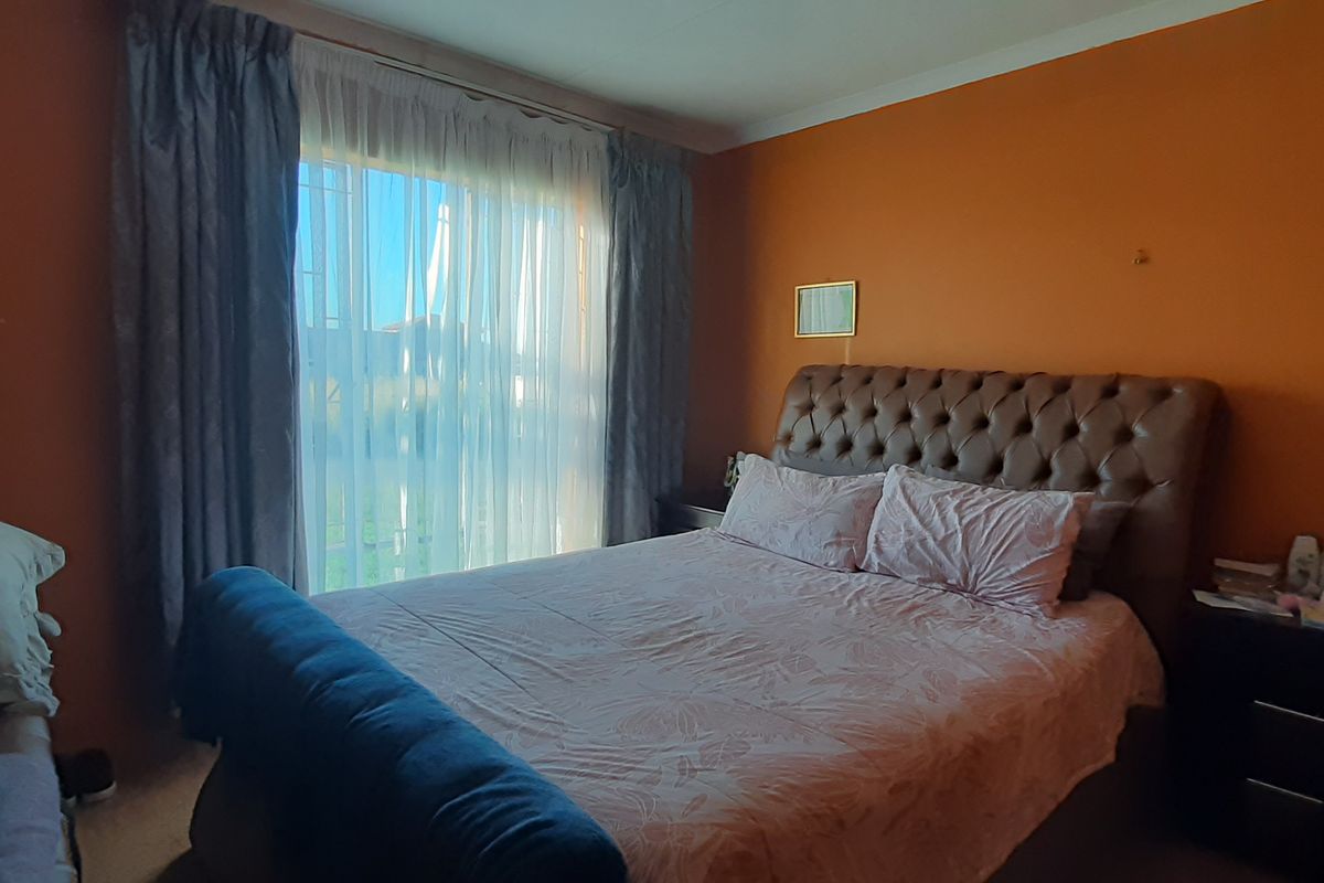 A bedroom featuring a sliding glass door with curtain tracks and orange painted walls showing signs of wear.