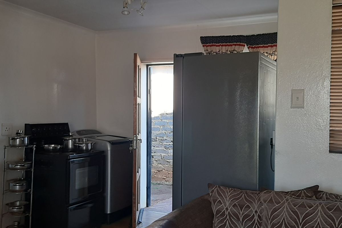 A functional kitchen area featuring a freestanding stove, stone-cladding accent wall, and direct access to the exterior.