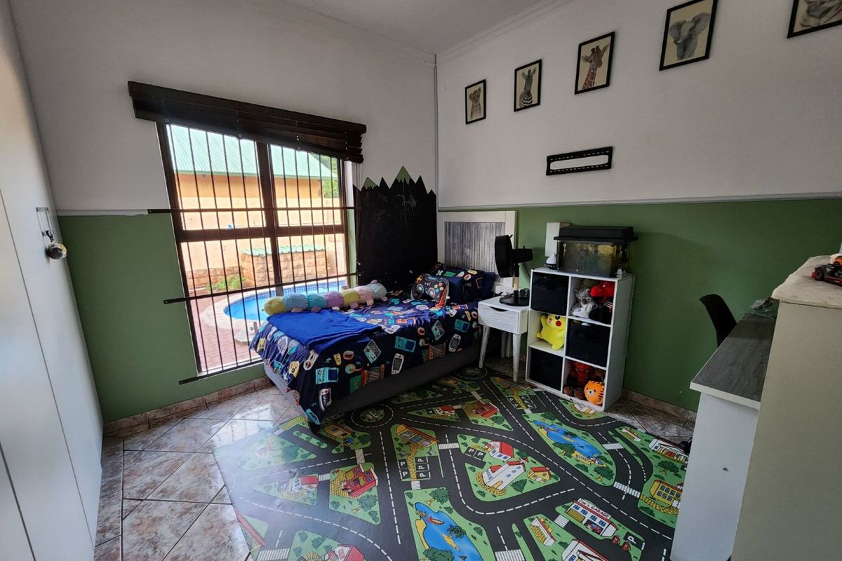 A bedroom featuring tiled flooring, built-in cabinetry, and a large window with security bars overlooking the pool area.