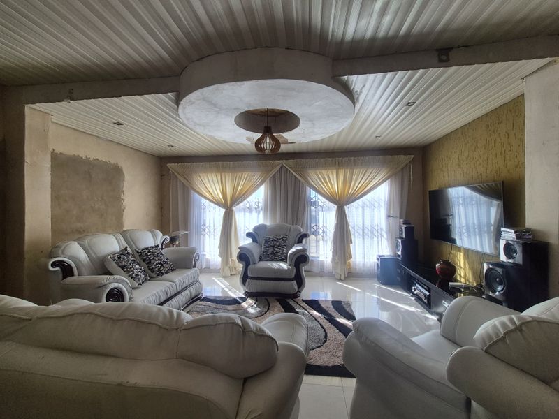 Spacious living room featuring tiled floors, a textured accent wall, and a unique circular recessed ceiling feature, currently requiring cosmetic wall finishing.