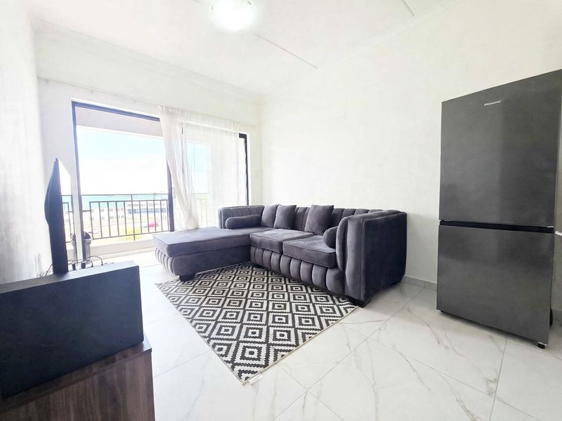 Open plan living area featuring modern tiled flooring and a sliding glass door providing direct access to a balcony with coastal views.
