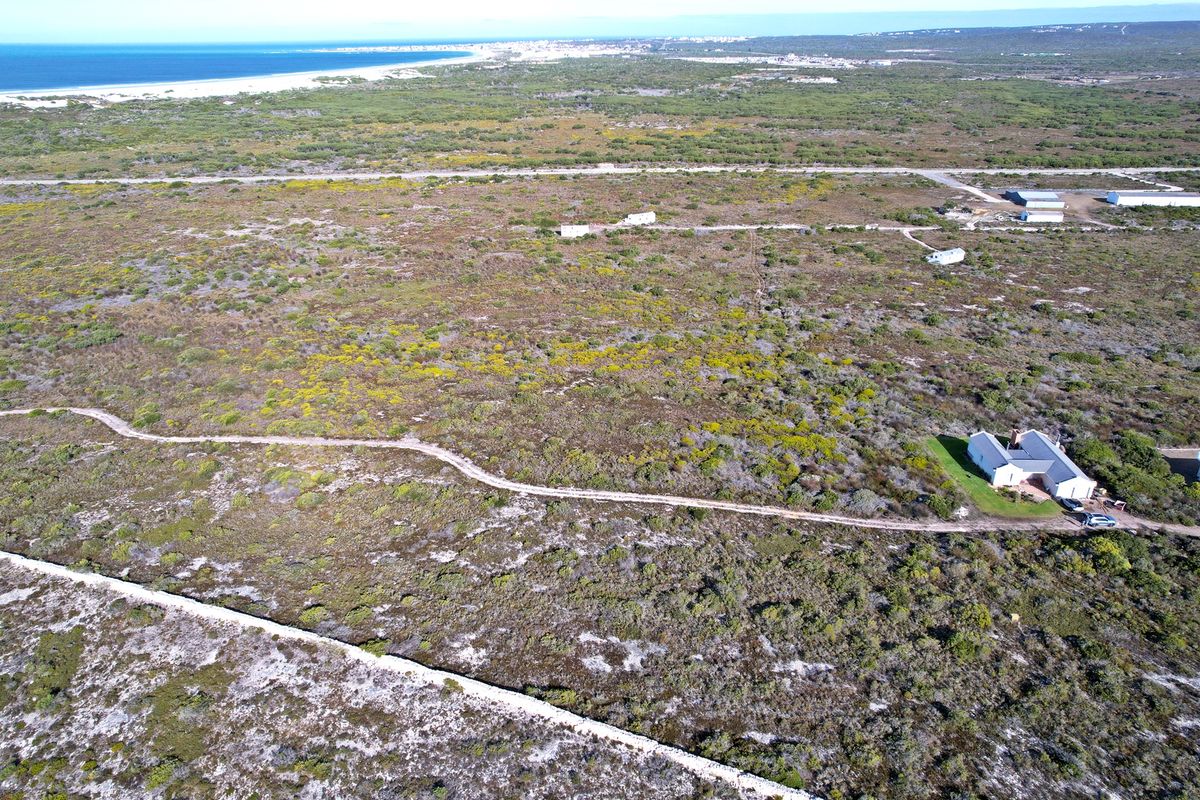 An aerial view of a large, undeveloped residential land parcel featuring natural coastal vegetation and proximity to the coastline.