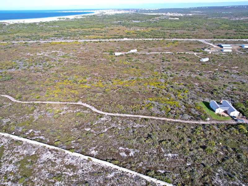 An aerial view of a large, undeveloped residential land parcel featuring natural coastal vegetation and proximity to the coastline.