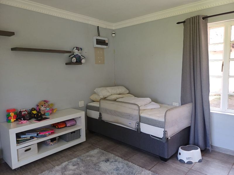 A bedroom featuring tiled flooring, crown molding, and a window with curtaining, providing a functional space with basic fixed finishes.