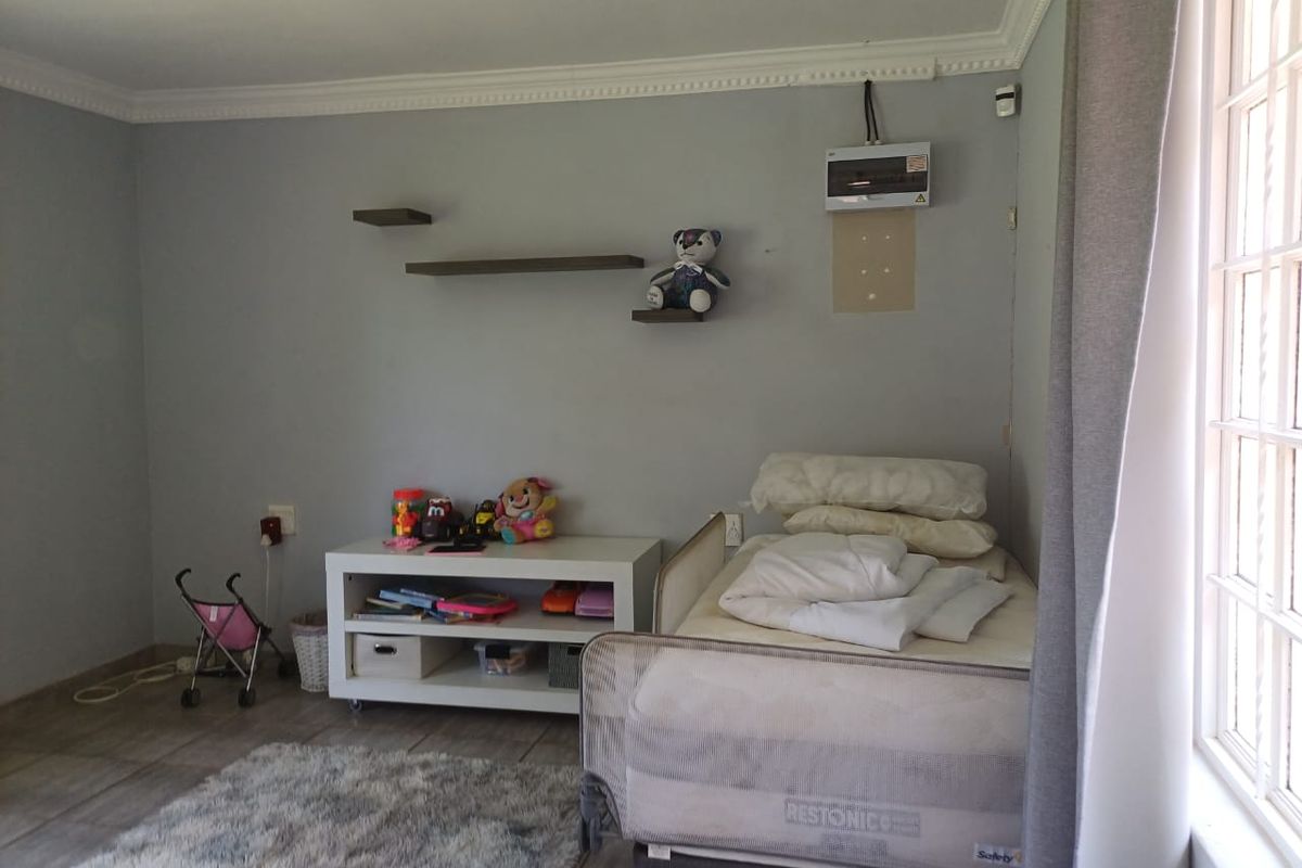 A bedroom featuring tiled flooring, crown molding, and a wall-mounted electrical distribution board.