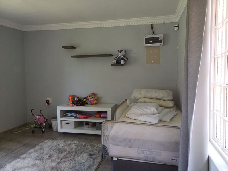 A bedroom featuring tiled flooring, crown molding, and a wall-mounted electrical distribution board.
