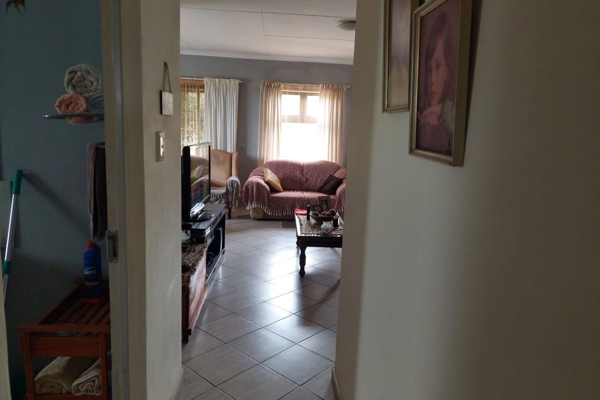 A view from a hallway into a living room featuring tiled flooring and natural light from a window.