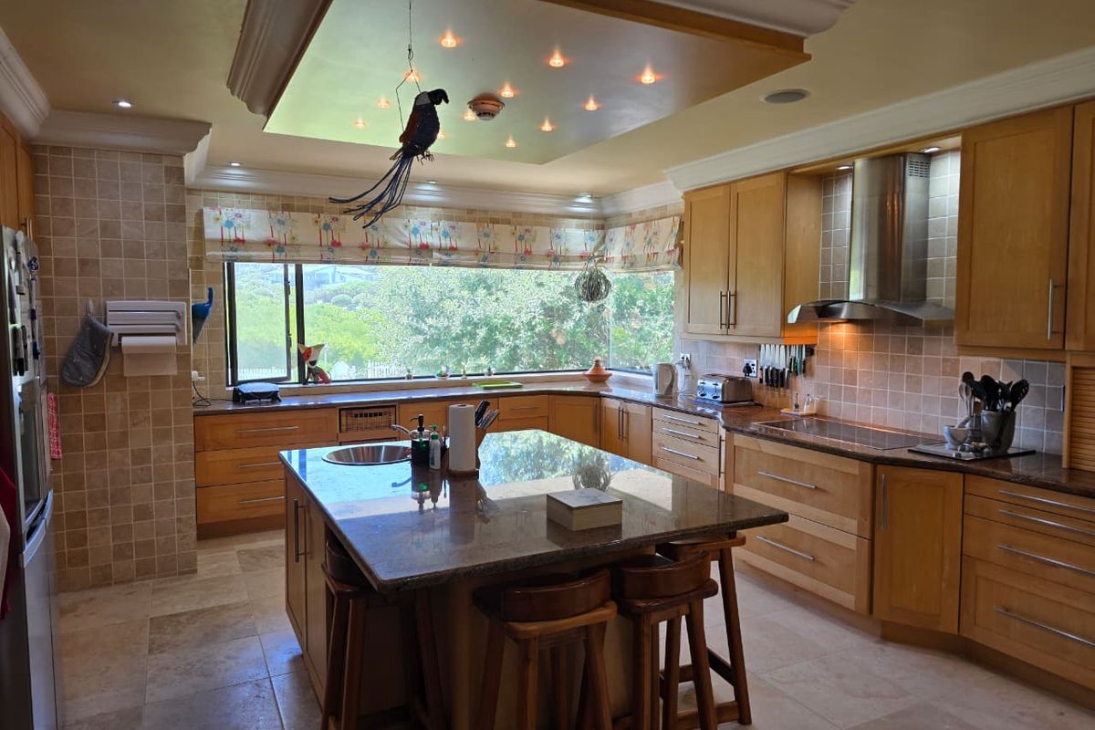 Spacious kitchen featuring light wood cabinetry, granite countertops, a central island with sink, and recessed lighting, offering a functional and well-maintained cooking space.