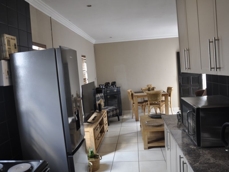 Open-plan living and kitchen area featuring tiled flooring, granite countertops, and neutral wall tones, offering a functional layout for daily living.