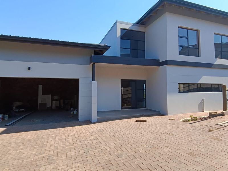 Modern double-storey cluster home featuring a paved driveway, double garage, and contemporary architectural design with clean lines and aluminium window frames.