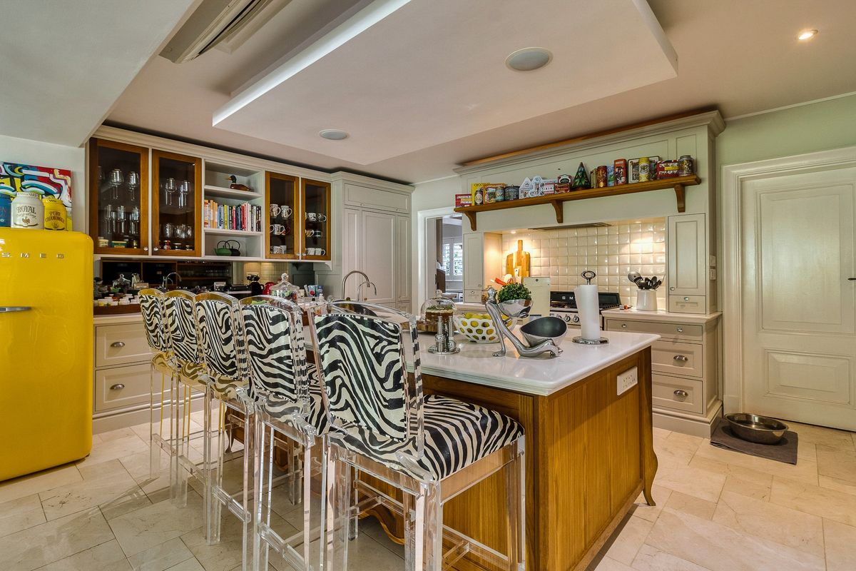 A well-appointed kitchen featuring a central island with stone countertops, custom cabinetry, tiled backsplash, and recessed lighting, offering a functional and stylish culinary space.