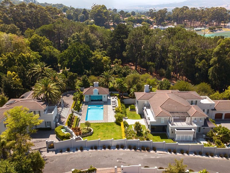 Aerial view of a large residential estate featuring a swimming pool, pool house, landscaped gardens, and multiple structures with tiled roofs.