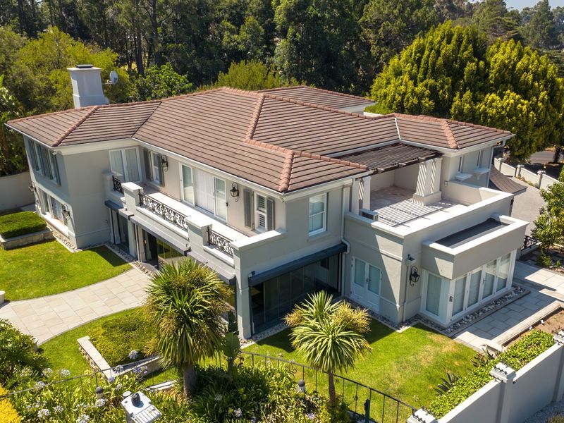Aerial view of a well-maintained multi-story residence featuring a tiled roof, balcony with wrought iron railings, pergola, and landscaped garden areas.